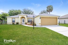 Palm Bay house for rent - a yellow house with a lawn and a garage