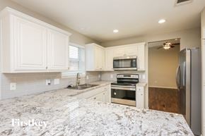 Fort Worth house for rent - a white kitchen with stainless steel appliances and marble counter tops