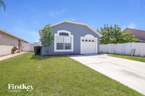 Kissimmee house for rent - a blue house with a driveway and a white fence