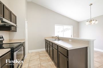 Kissimmee house for rent - a kitchen with an island and a stove and a window
