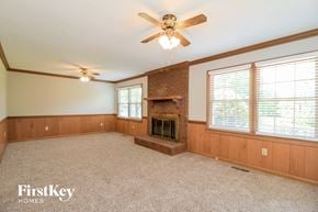High Point house for rent - a living room with a brick fireplace and a ceiling fan