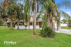Rockledge house for rent - a yard with palm trees and a house in the background