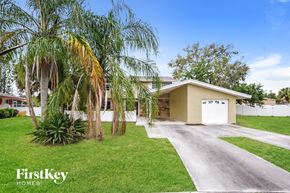 Rockledge house for rent - a home with palm trees on the lawn and a driveway
