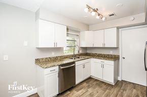 Rockledge house for rent - a kitchen with white cabinets and granite counter tops and a stainless steel sink