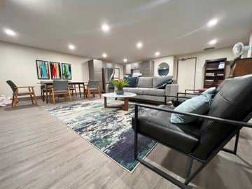 Regina apartment for rent - A living room with a black leather sofa and a rug.