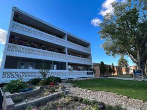 Regina apartment for rent - A white building with balconies and a garden in front.