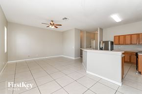Lehigh Acres house for rent - an empty living room with a kitchen and a ceiling fan