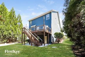 Newnan house for rent - A blue house with a wooden deck and stairs leading to the entrance.