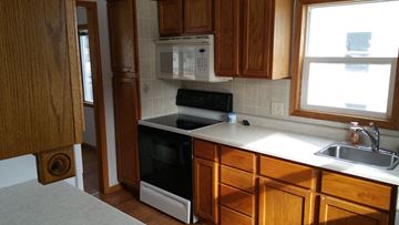 Grand Forks house for rent - a kitchen with wooden cabinets and a black stove