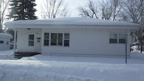 Grand Forks house for rent - A white house with snow on the roof and ground.
