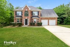 Mcdonough house for rent - a brick house with a green lawn and a white garage