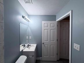 East Point apartment for rent - A bathroom with a toilet, sink, mirror, and light fixture.