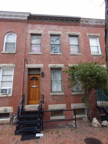 Washington apartment for rent - A red brick building with a wooden door and a tree in front.