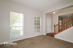 O'fallon house for rent - A room with a carpeted floor, a staircase, and a window with blinds.
