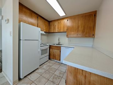 Hayward apartment for rent - A kitchen with a white refrigerator, wooden cabinets, and a white countertop.