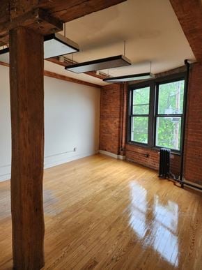 Brattleboro apartment for rent - A room with wooden floors and a large window with a view of trees outside.