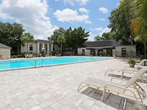 Winter Park apartment for rent - A pool surrounded by lounge chairs and trees.