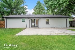 Garland house for rent - A house with a white exterior and a brown door is surrounded by green grass.