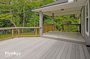 Jacksonville house for rent - A wooden deck with a white house and trees in the background.