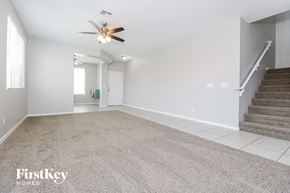 Waddell house for rent - a carpeted living room with stairs and a ceiling fan