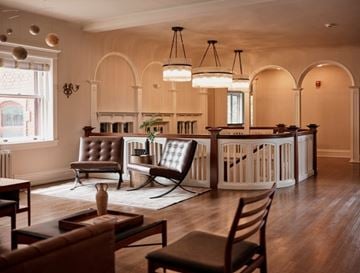 Cleveland Heights apartment for rent - A living room with a brown leather chair and a white chair with a wooden table and a fireplace.