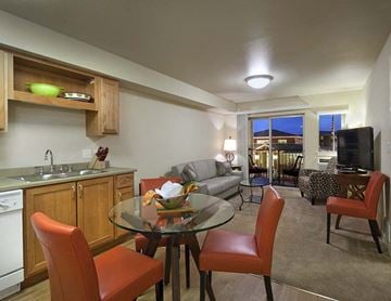 Boise apartment for rent - A kitchen with a table and chairs in the foreground and a balcony with a couch and chairs in the background.