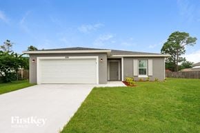 Palm Bay house for rent - A two-car garage with a white door is situated in a grassy area.
