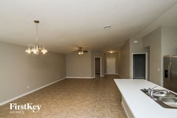 Palm Bay house for rent - A kitchen with a sink and a fridge in a room with tiled flooring.