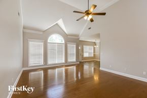 Mcdonough house for rent - an empty living room with a ceiling fan and large windows