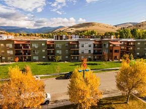Missoula apartment for rent - A view of apartment buildings with a car and trees in the foreground.