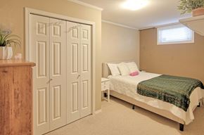 Saskatoon apartment for rent - A bedroom with a bed, nightstand, and a plant.