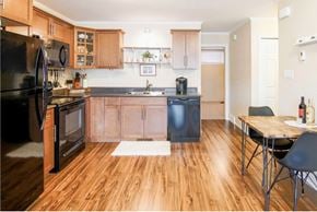Saskatoon apartment for rent - A kitchen with a black refrigerator and wooden floors.