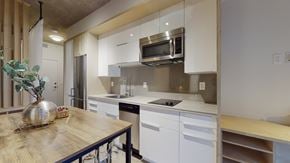 Edmonton apartment for rent - a kitchen with white cabinets and a wooden table