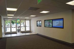 Brea apartment for rent - A hallway with a green exit sign above the door and a monitor on the wall.