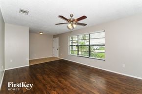 Cape Coral house for rent - an empty living room with a ceiling fan and a large window