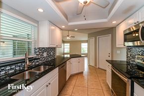Cape Coral house for rent - a kitchen with black counter tops and white cabinets and a sink