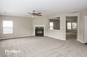 Charlotte house for rent - A spacious living room with a fireplace and a ceiling fan.