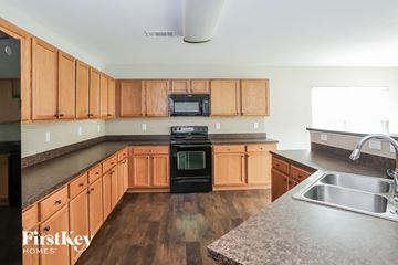 Charlotte house for rent - A kitchen with wooden cabinets and a black stove top oven.