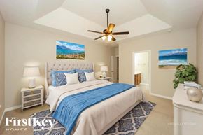 Dallas house for rent - A bedroom with a bed, a ceiling fan, and a painting of a beach scene on the wall.