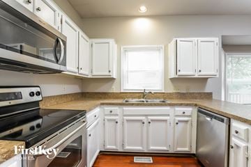 Greensboro house for rent - a kitchen with white cabinets and a stove and a sink