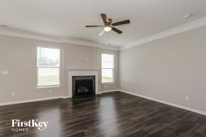 Mooresville house for rent - A spacious room with a fireplace and a ceiling fan.