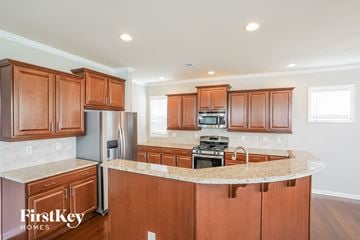 Clayton house for rent - A kitchen with wooden cabinets and a marble countertop.