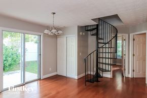 Alpharetta house for rent - A spacious room with a wooden floor and a black spiral staircase.