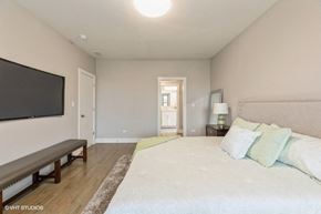 Chicago apartment for rent - a master bedroom with a large bed and a tv