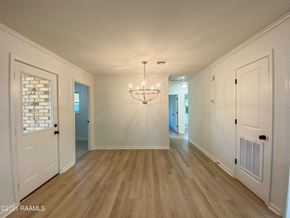 Carencro house for rent - the living room and dining room of a house with white walls and wood floors