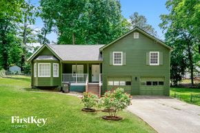 Suwanee house for rent - the front of a green house with trees and a driveway