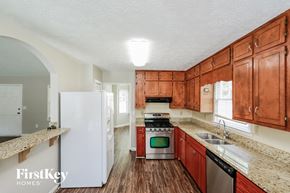 Suwanee house for rent - a kitchen with wooden cabinets and white appliances