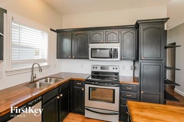Whitestown house for rent - A kitchen with black cabinets and a stove top oven.