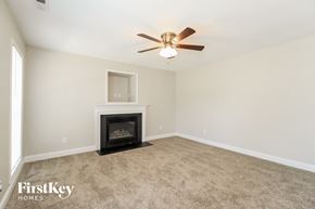Winston-Salem house for rent - A living room with a fireplace and a ceiling fan.