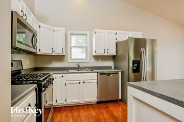 Wentzville house for rent - a kitchen with white cabinets and stainless steel appliances